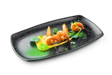 Soslu kızarmış karides, beyaz arka planda izole edilmiş mikroyeşilliklerle süslenmiş. Balık ve deniz ürünleri, yakın çekim, üst manzara.