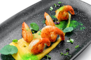 Soslu kızarmış karides, beyaz arka planda izole edilmiş mikroyeşilliklerle süslenmiş. Balık ve deniz ürünleri, yakın çekim, üst manzara.