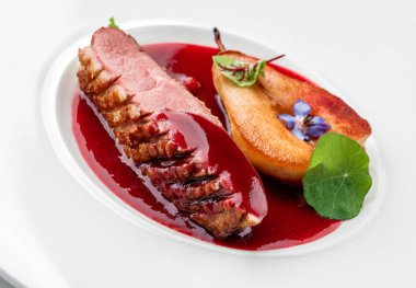 Izgara biftek ya da ızgara biftek madalyonu. Beyaz arka planda izole edilmiş fırında armut ve sosla birlikte. Et tabakları, üst manzara, kapatın.