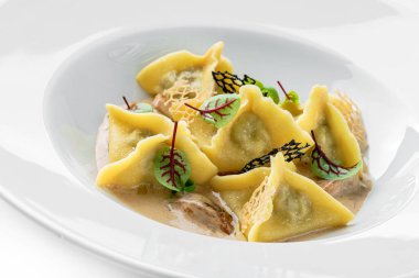 Soslu Ravioli, beyaz arka planda izole edilmiş yeşil tabakla süslenmiş. İtalyan yemekleri, üst manzara, kapat.