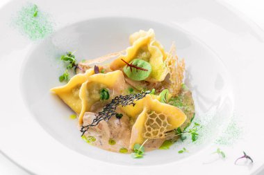 Soslu Ravioli, beyaz arka planda izole edilmiş yeşil tabakla süslenmiş. İtalyan yemekleri, üst manzara, kapat.