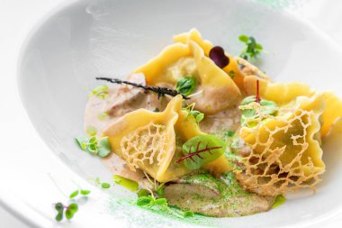 Soslu Ravioli, beyaz arka planda izole edilmiş yeşil tabakla süslenmiş. İtalyan yemekleri, üst manzara, kapat.