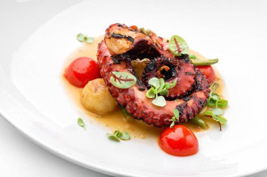 Beyaz arka planda izole edilmiş sebze ve soslu ızgara ahtapot. Sağlıklı yemek, üst manzara, yakın çekim.