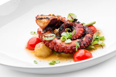 Beyaz arka planda izole edilmiş sebze ve soslu ızgara ahtapot. Sağlıklı yemek, üst manzara, yakın çekim.