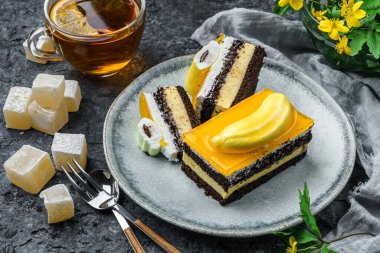 Muzlu kremalı çikolatalı bisküvi ve gri arka planda bir fincan çay, meyve ve çiçekli meyve jölesi. Tatlılar, tatlı ve pasta, üst manzara