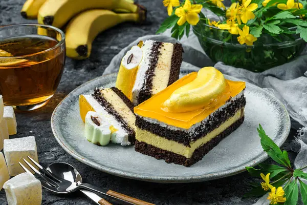 Muzlu kremalı çikolatalı bisküvi ve gri arka planda bir fincan çay, meyve ve çiçekli meyve jölesi. Tatlılar, tatlı ve pasta, üst manzara