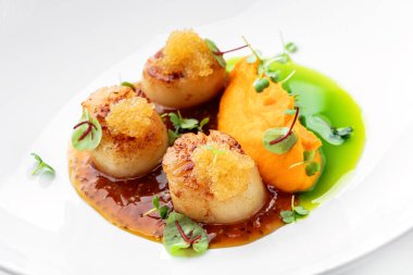 Balık havyarlı kızarmış deniz tarağı ve beyaz arka planda izole edilmiş tabakta sos. Deniz ürünleri, yakın çekim, üst manzara.