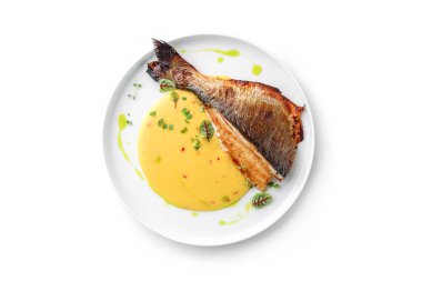 Soslu ızgara fileto Dorado balığı ve beyaz arka planda izole edilmiş tabakta yeşillikler. Sağlıklı deniz ürünleri, üst manzara, yakın çekim.