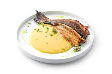 Soslu ızgara fileto Dorado balığı ve beyaz arka planda izole edilmiş tabakta yeşillikler. Sağlıklı deniz ürünleri, üst manzara, yakın çekim.