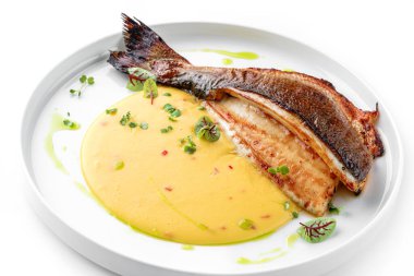 Soslu ızgara fileto Dorado balığı ve beyaz arka planda izole edilmiş tabakta yeşillikler. Sağlıklı deniz ürünleri, üst manzara, yakın çekim.