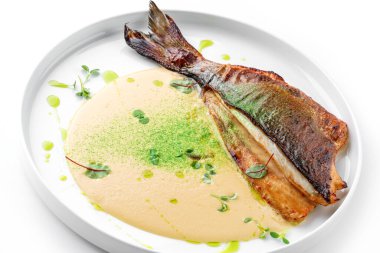 Soslu ızgara fileto Dorado balığı ve beyaz arka planda izole edilmiş tabakta yeşillikler. Sağlıklı deniz ürünleri, üst manzara, yakın çekim.