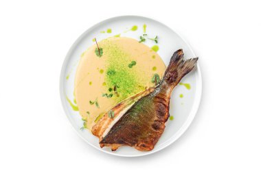 Soslu ızgara fileto Dorado balığı ve beyaz arka planda izole edilmiş tabakta yeşillikler. Sağlıklı deniz ürünleri, üst manzara, yakın çekim.