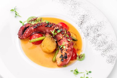 Beyaz arka planda izole edilmiş sebze ve soslu ızgara ahtapot. Sağlıklı yemek, üst manzara, yakın çekim.