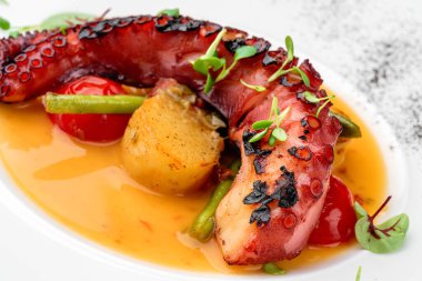 Beyaz arka planda izole edilmiş sebze ve soslu ızgara ahtapot. Sağlıklı yemek, üst manzara, yakın çekim.