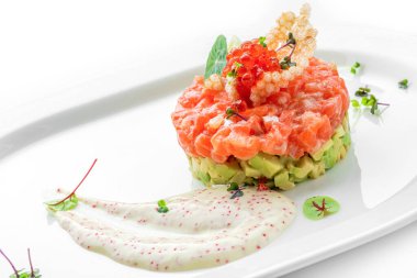 Somon balığı, avokado ve kırmızı havyarlı tart. Beyaz arka planda izole edilmiş tabakta mikroyeşillikler var. Balık ve deniz ürünleri, yakın çekim, üst manzara.