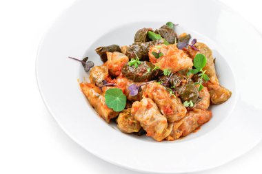 Dolma, lahana ruloları, beyaz arka planda izole edilmiş tabakta ekşi krema ile doldurulmuş üzüm yaprakları. Geleneksel yemekler, üst manzara, kapat