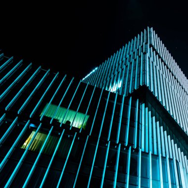 Açık mavi çizgili dikey cam şeritli modern binanın gece fotoğrafı..