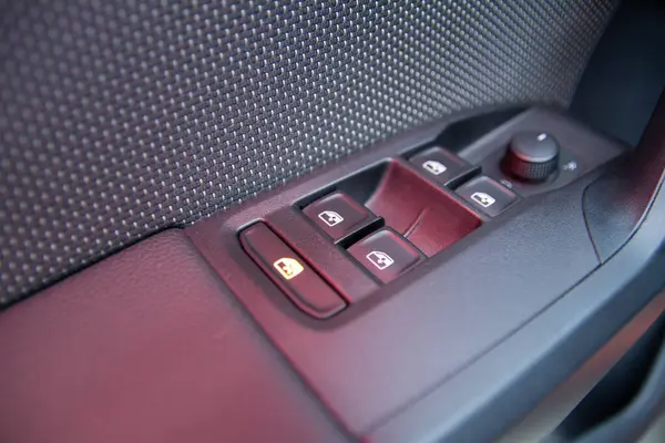 Ön sürücü kapısının yanındaki cam ve aynaların kontrol panelinin yakın çekim detayları. Parlayan kırmızı ışığın görünür yansımasına sahip karanlık kısımlar.. 
