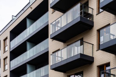 Koyu cam balkonlu ve açık tuğlalı apartman manzaralı, şehir mimarisi.