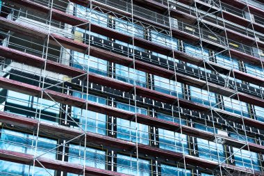 İnşaat halindeki yüksek binalar iskele ve cam panellerle kaplı.