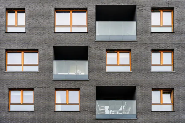 Simetrik pencereleri ve cam balkonları olan modern apartman cephesi, kentsel konut mimarisi