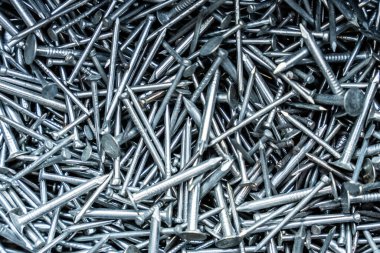 Yoğun bir yığına dağılmış metal çiviler, parlak gümüş yüzeyleri ve sivri dokuları olan inşaat malzemeleri konsepti
