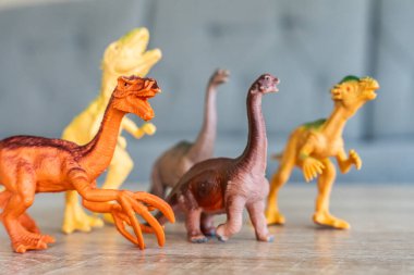 Tahta yüzeydeki renkli dinozor figürleri tarih öncesi yaratıkları ve yaratıcı çocukluk oyunlarını temsil ediyor.