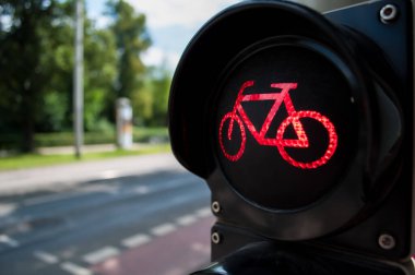 Şehir caddesinde gündüz vakti kırmızı bisiklet trafik ışığı yanıyor. Ulaşım güvenliği kavramında bisikletçilerin durduğunu gösteriyor.