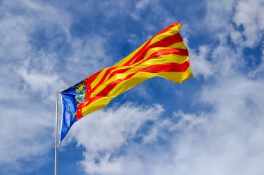 Rüzgarda sallanan renkli Valensiyalı bayrağı dramatik bulut oluşumlarıyla mavi gökyüzüne karşı kimlik ve gururu temsil ediyor.