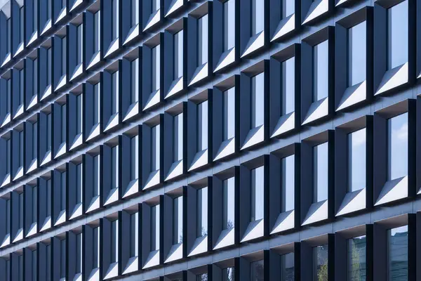 Tekrarlanan modern ofis binası ön cephesi dikdörtgen pencereler soyut geometrik desenler, gündüz mimari arka plan