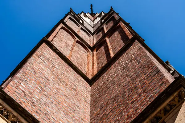 Wroclaw, Polonya 'da açık mavi gökyüzüne karşı tarihi kırmızı tuğla bir kilise kulesinin keskin köşesine bakarak dikey çizgileri ve gotik mimariyi vurguluyorum.