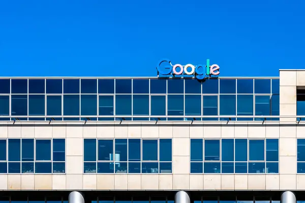 Polonya 'daki modern ofis binasının tepesinde cam perade ve Google logosu var. Güneşli bir günde mavi gökyüzünün altında çekilmiş.
