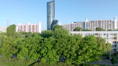 Wroclaw 'daki gökdelen gökdeleninin hava görüntüsü yeşil park bölgesinden geliyor. Açık mavi gökyüzü günü