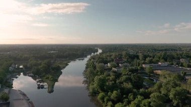 Polonya 'da altın saatinde ağaçlar ve kentsel gelişim ile çevrili Odra nehrinin havadan görünüşü