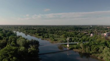 Nehir üzerinde yemyeşil zemin ve mavi gökyüzü ile beyaz çelik süspansiyon köprü kapalı havası