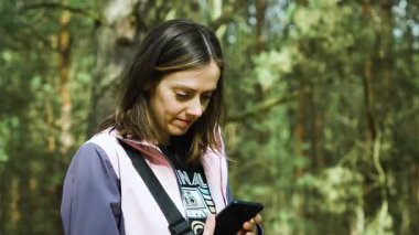 Polonya ormanlarında akıllı telefon kullanan bir kadın bahar aylarında doğal orman ortamında teknolojiye odaklanıyor.