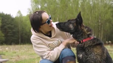 Orman temizliğinde Alman çoban köpeğiyle sevgi dolu bir bağ kuran kadın, neşeli ifadeler, arkadaşlık.