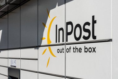 Posta kutusunun dış tarafında şirket logosu ve slogan var. Gündüz beyaz paneller, Polonya, modern şehir servis altyapısı.