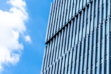 Mavi gökyüzüne karşı dikey pencere desenli modern cam ofis cephesi, Polonya 'da kentsel mimari