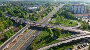 Baharda hareket eden trafik ve yeşil ağaçlarla çoklu yol kesişiminin havadan görüntüsü