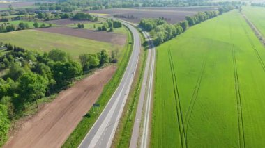 Yeşil alanlar ve seyrek trafik ile kırsal alanda dolambaçlı yolun hava manzarası, ilkbahar ulaşımı kavramı