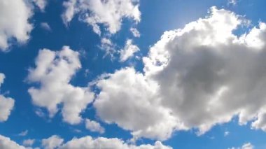 Pofuduk beyaz bulutlar parlak güneşli, mavi gökyüzünde hareket ediyor. Hava ve çevre için ideal dramatik bir atmosfer.