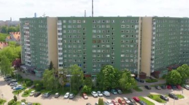 Polonya 'daki tipik bir Doğu Avrupa konut binasının insansız hava aracı görüntüleri yeşil bir cephe, park edilmiş arabalar ve gün ışığı altındaki ağaçların çevresini gösteriyor..