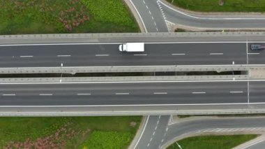 Yeşil alanlarla çevrili, dar ve bitişik giriş ve çıkış yolları olan, çok şeritli, yüksek bir otoyolun insansız hava aracı görüntüleri. Modern yol altyapısını ve ulaşım planlarını gösterir.