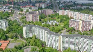 Polonya 'da ağaçlar ve şehir yeşillikleriyle çevrili yüksek binaların insansız hava aracı görüntüsü, organize şehir planlarını ve savaş sonrası konut mimarisini betimliyor..