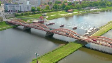 Polonya 'nın Wrocaw kentindeki Oder Nehri' nden geçen, yakınındaki Weir, karayolları ve binalarla şehir altyapısını ve ulaşımını gösteren belirgin bir kırmızı köprünün hava görüntüleri..