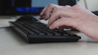 Bilgisayar faresi ve klavye kullanan bir kişinin yavaş çekim görüntüsü, modern çalışma ortamında günlük dijital aktiviteleri ve ofis rutinlerini vurguluyor.