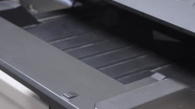 Ofis yazıcısı, çizelgeleri ve metni olan profesyonel bir belge hazırlıyor. Video, baskı teknolojisi ve iş belgelerinin vurgulandığı tipik ofis ekipmanlarını vurguluyor.