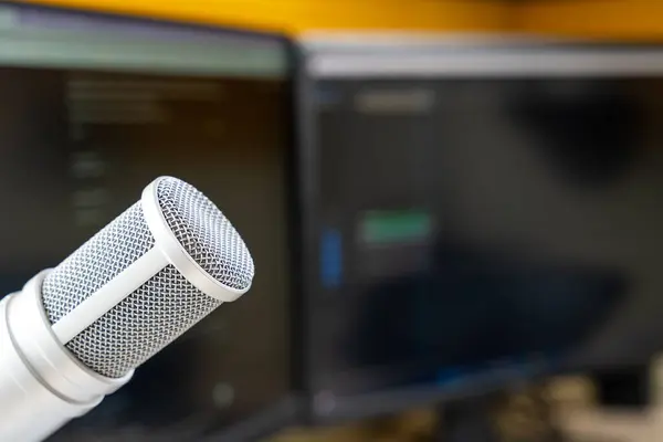 Ses düzenleme yazılımını gösteren bulanık arkaplan ekranlarıyla stüdyoda yoğunlaştırıcı mikrofon, podcast görselleri için ideal
