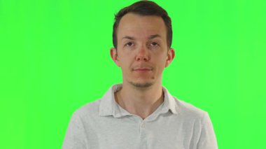 Beyaz gömlekli bir erkek, öne bakıyor ve bazen yukarı bakıyor. Krom anahtar arka planda sakin, nötr bir tavır sergiliyor.